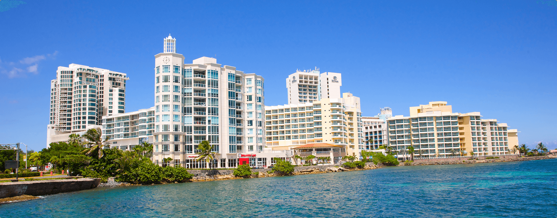Edificios de condominios frente al mar bajo un cielo azul en Puerto Rico.